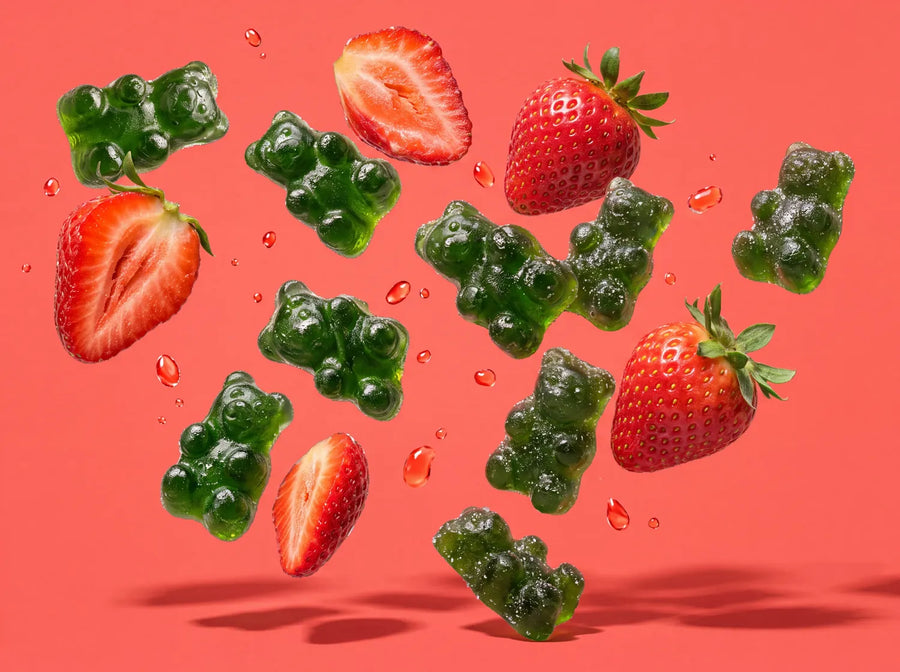 Green gummy bears and fresh strawberries flying on a coral background