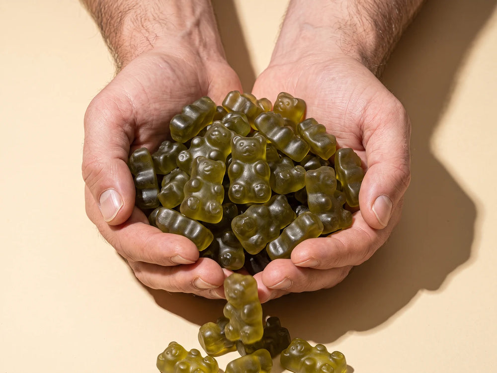 Two hands overflowing with green Superfood Greens Gummies