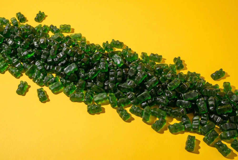 A long river of green gummy bears on a yellow background