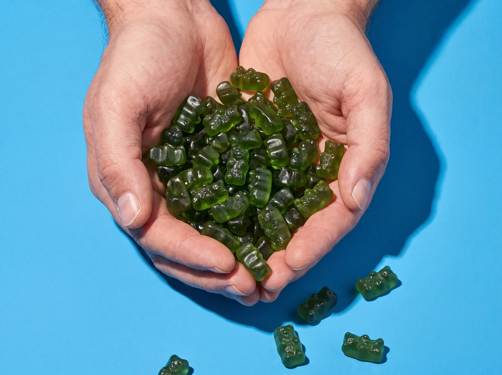 Two cupped hands full of green strawberry gummies
