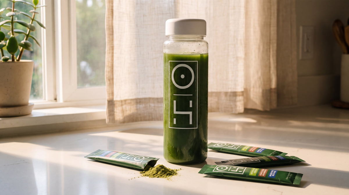 A bottle of Optimal Human Superfood Greens on a kitchen counter next to the stick packs