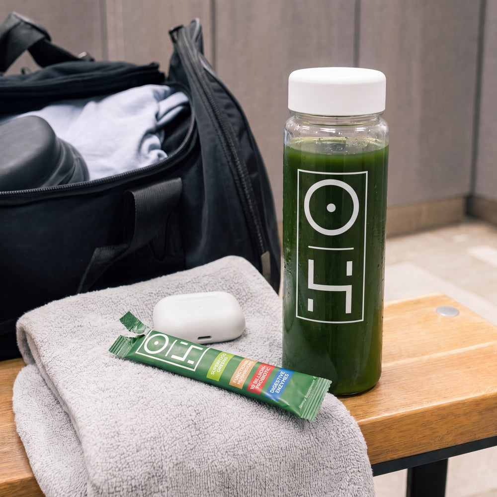 A gym bag with a bottle of greens and an Optimal Human stick on a towel