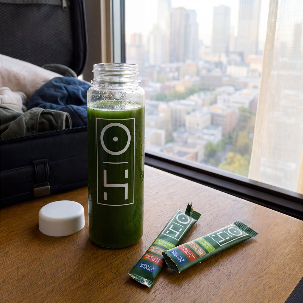 A bottle of Superfood Greens and two sticks on a hotel desk by the window