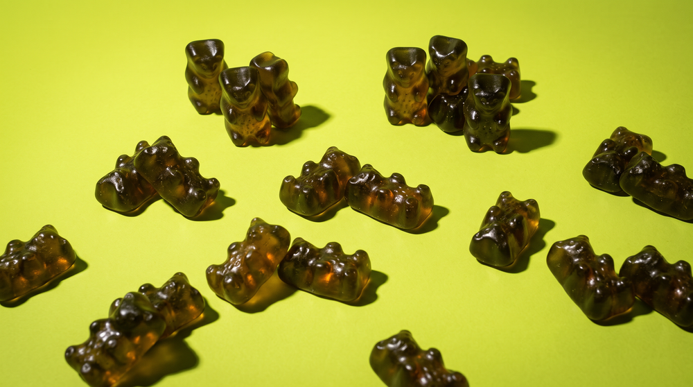 A loose scatter of green superfood gummies on a white surface