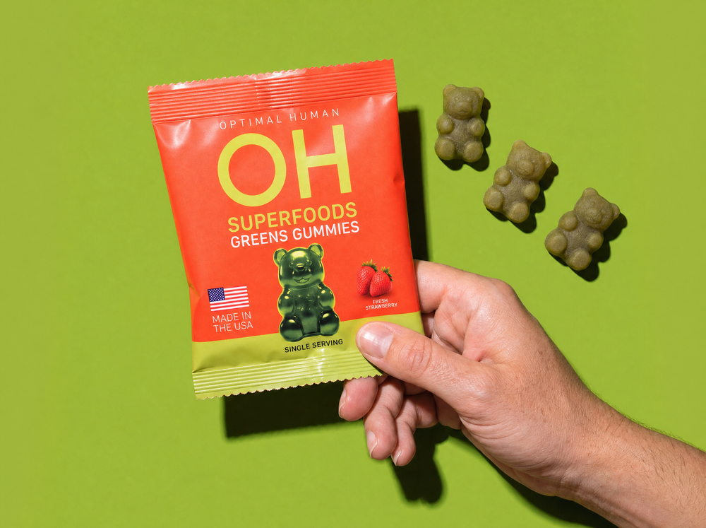 A hand holding a single-serve pack of Superfood Greens Gummies