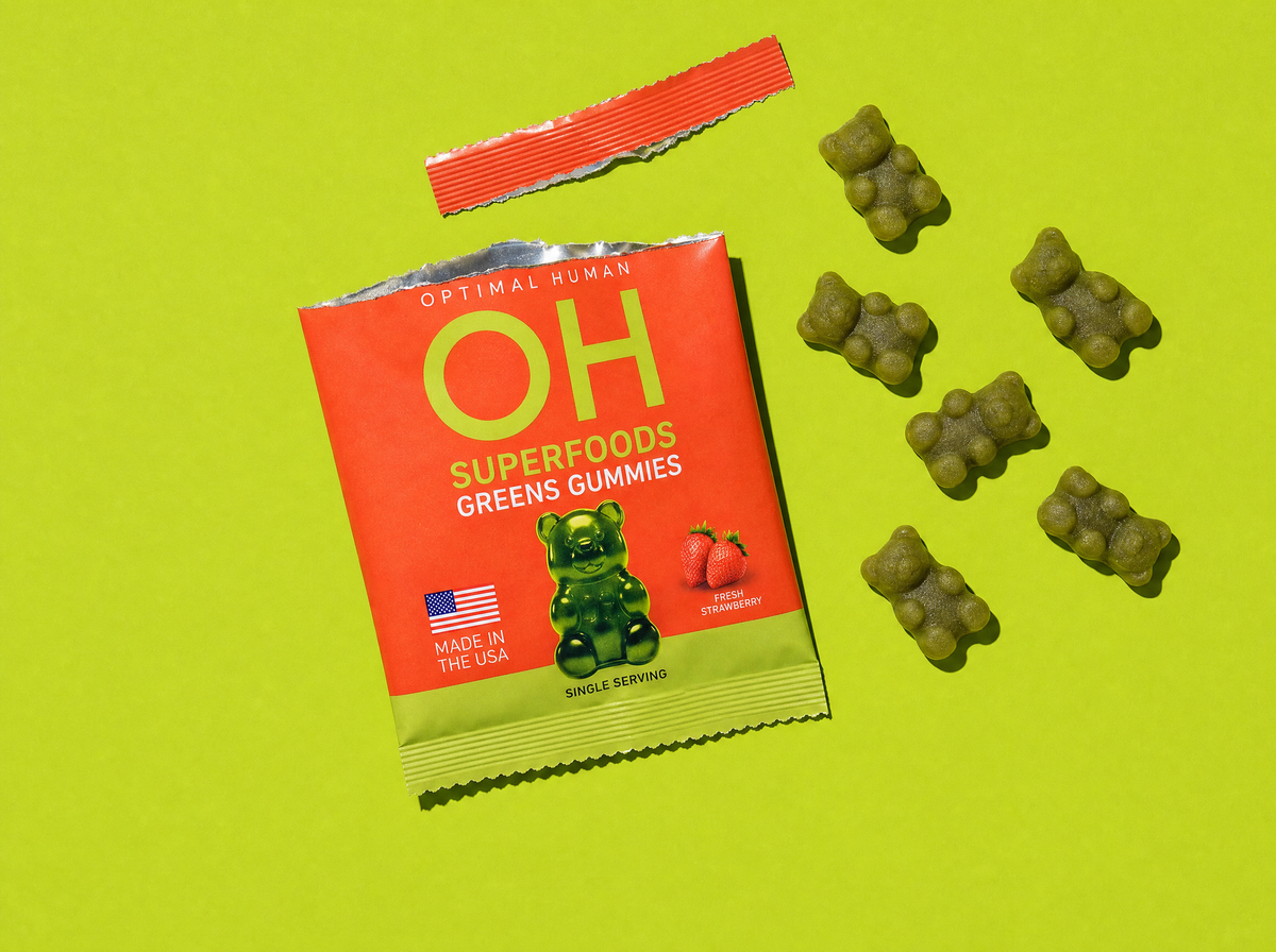 An opened single-serve pack with its torn strip and six green gummies beside it
