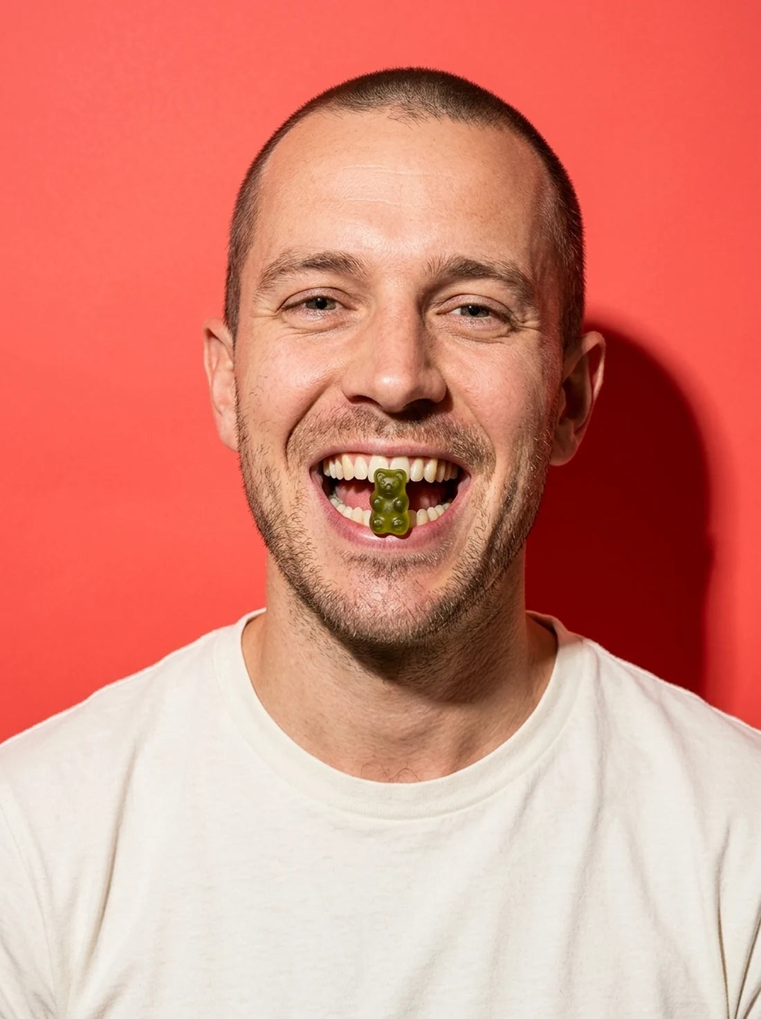 A man grinning with a green gummy between his teeth