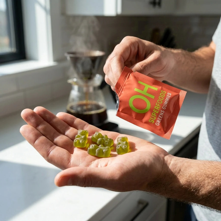 A hand holding an open Optimal Human gummies pack over a palm full of green gummies