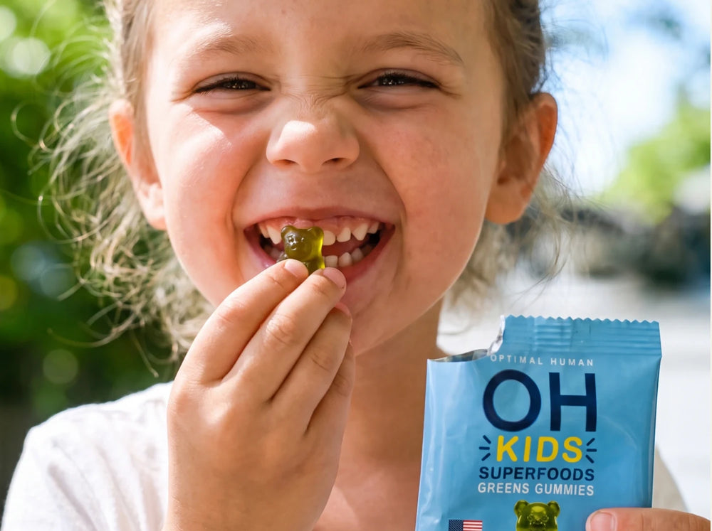 A little girl laughing with a green gummy and an OH Kids pack