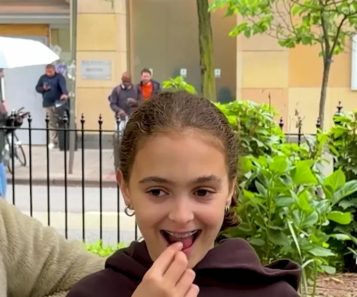 A girl in the park biting into a green gummy