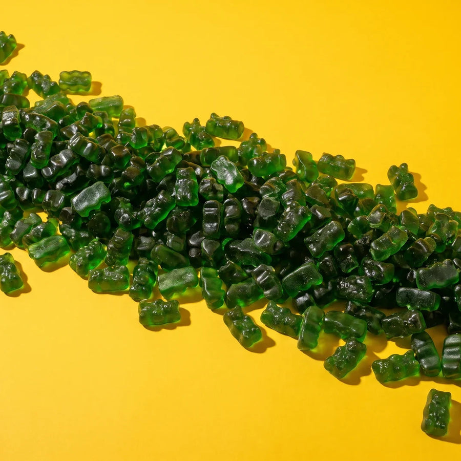 A long river of green gummy bears on a yellow background
