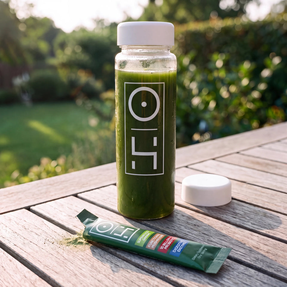 A bottle of mixed Superfood Greens on a sunny garden table, a stick pack beside it