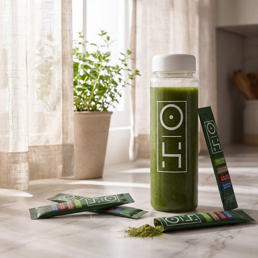 A bottle of mixed Superfood Greens on a kitchen counter next to stick packs