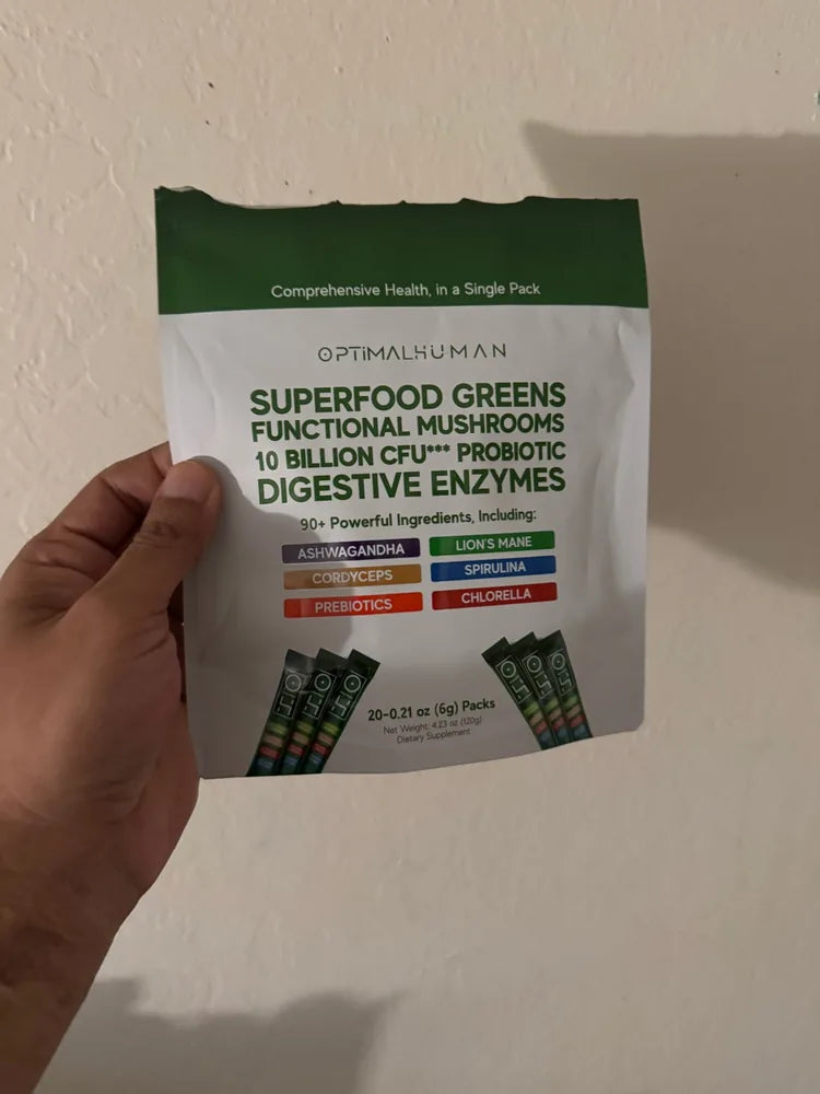 A customer photo of a hand holding a pouch of Optimal Human Superfood Greens single-serve sticks